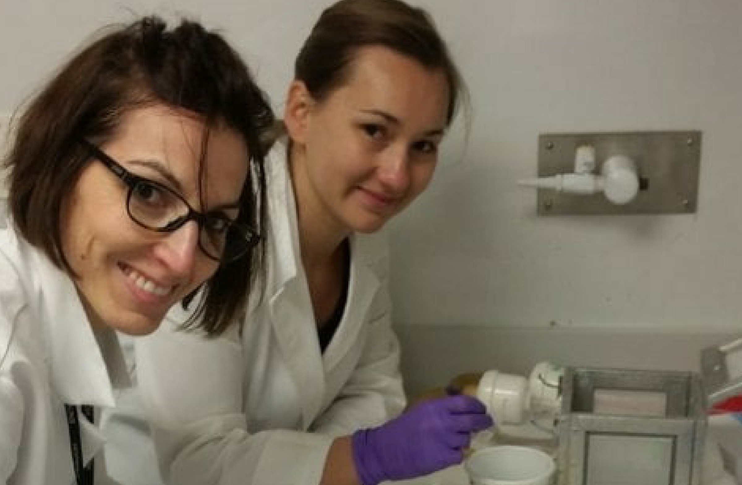 Due ricercatrici italiane al lavoro in laboratorio, impegnate nella ricerca per combattere le zanzare, sorridono davanti a un microscopio.