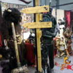 Immagine di una fiera del fumetto a Roma con costumi elaborati e segnali direzionali per eventi di cosplay, evidenziando l'atmosfera vivace del ROMICS.