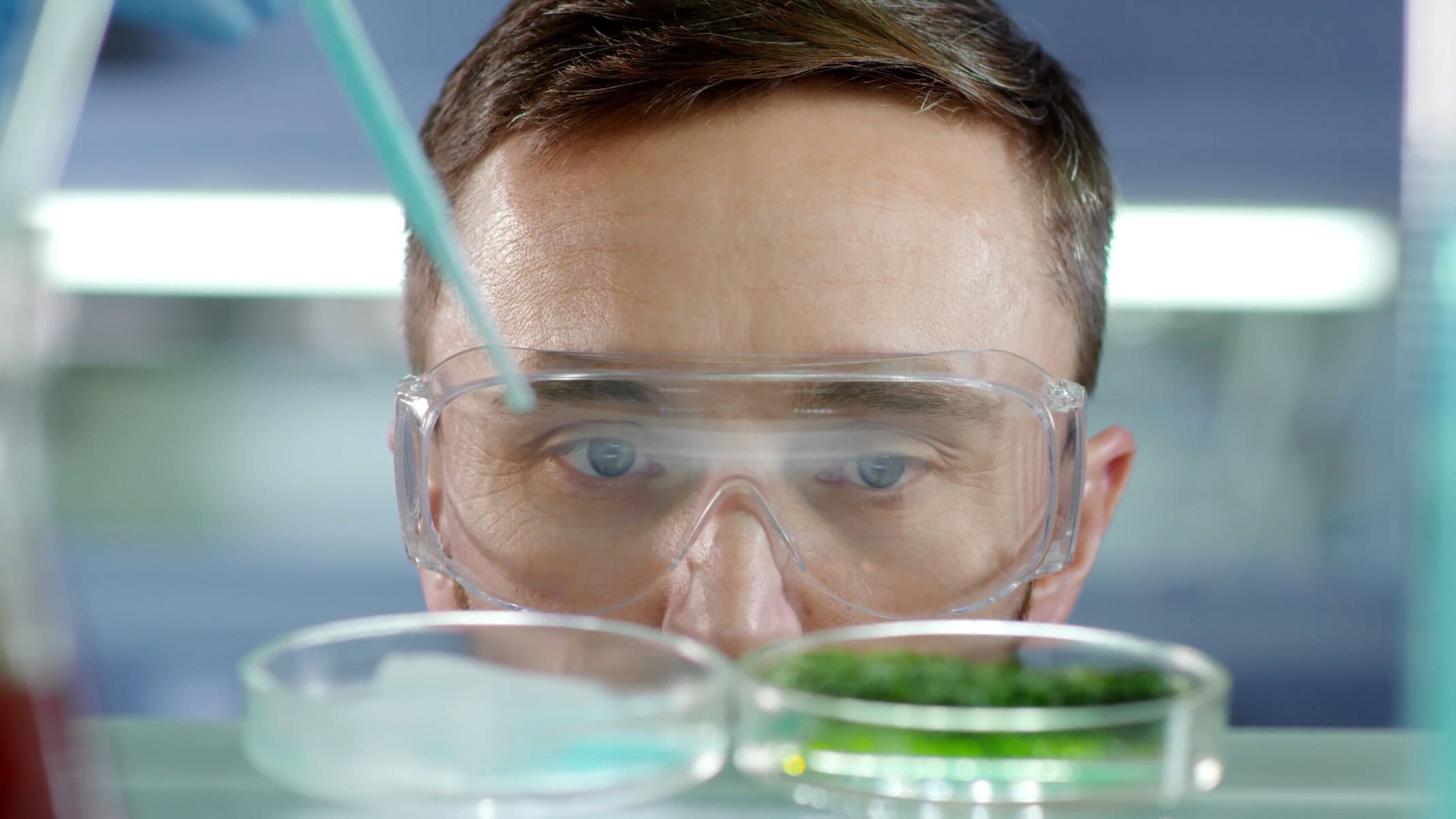 Ricercatore in laboratorio osserva campioni in provette, esplorando la carne coltivata, rappresentando l'innovazione scientifica.