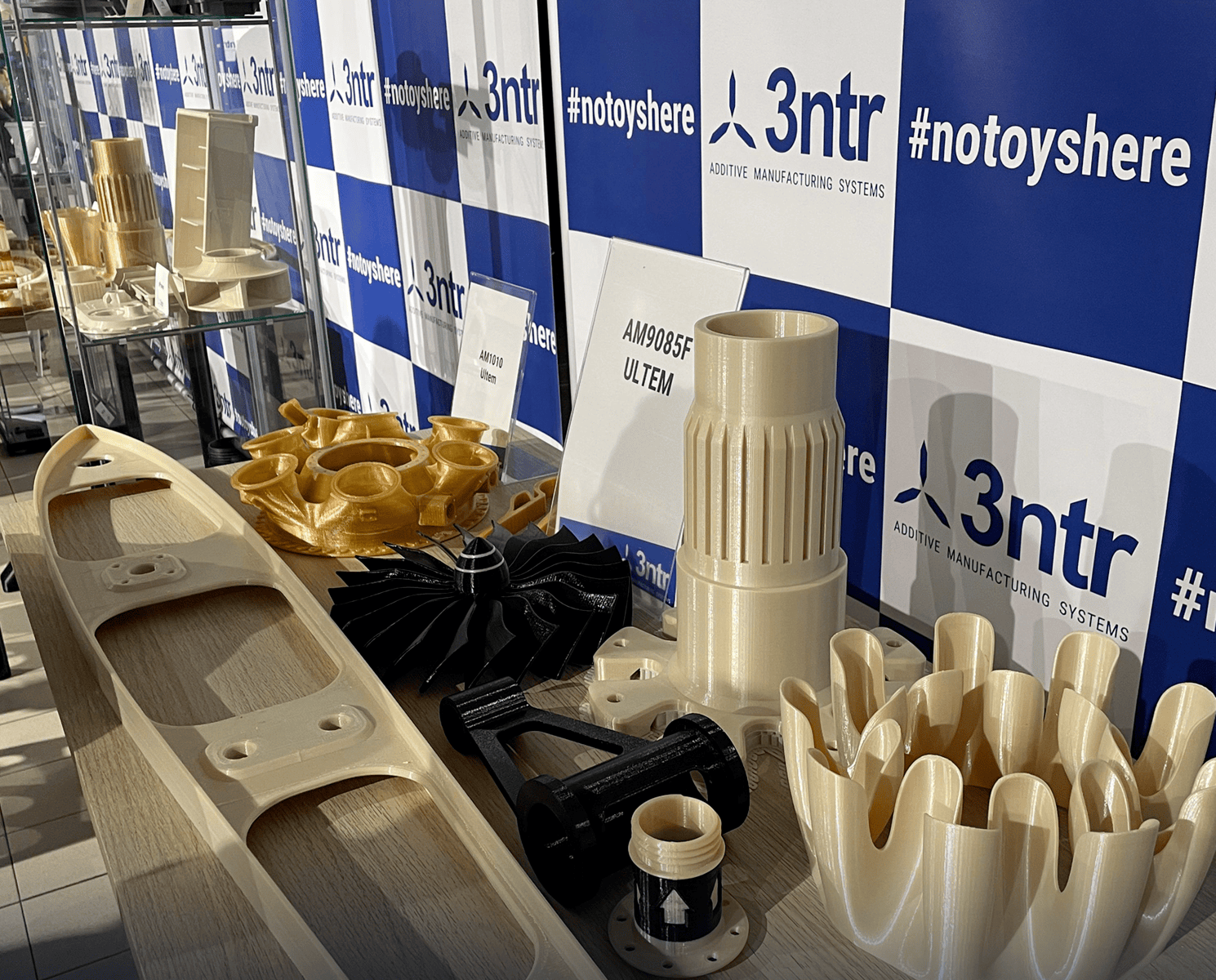 Componenti stampati in 3D esposti al booth di 3ntr, mostrando tecnologie avanzate di produzione additiva durante l'evento Bozza automatica.