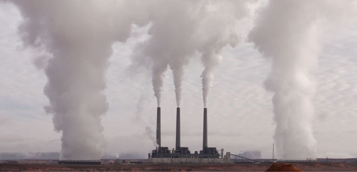 Impianto industriale con emissioni di fumi inquinanti, evidenziando l'impatto ambientale del gas liquefatto rispetto al carbone secondo Cornell University.