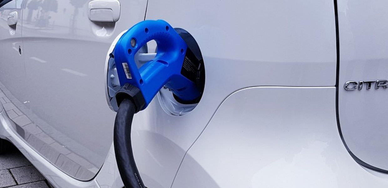 Ricarica dell'auto elettrica a casa, anche in condominio, con una stazione di ricarica installata su un veicolo bianco. Soluzioni pratiche disponibili.