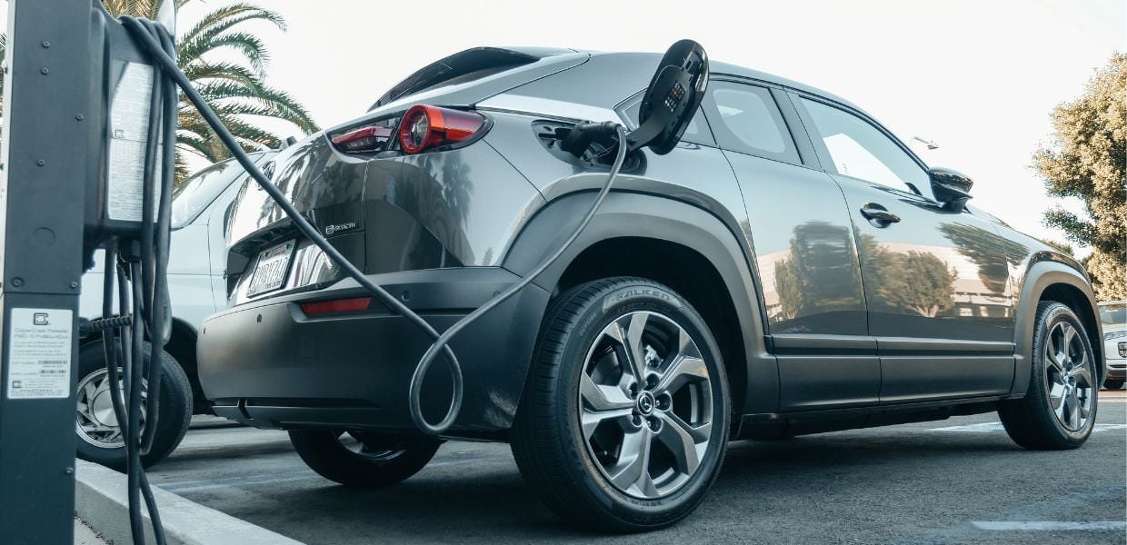 Auto elettrica in ricarica, evidenziando il calo dei costi previsto per il 2026 secondo uno studio sulle tendenze del mercato automobilistico.