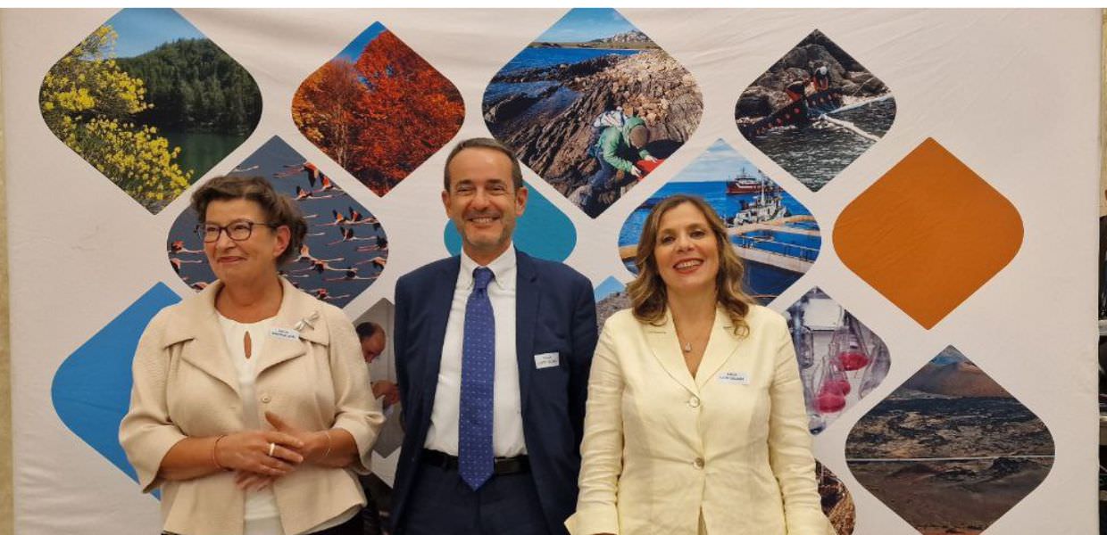 Immagine di tre persone in un evento legato all'Agenzia Europea dell'Ambiente, con uno sfondo colorato che rappresenta la natura e la sostenibilità.