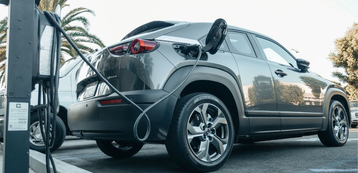 Auto elettrica in fase di ricarica su una stazione, simbolo del crescente mercato in UK e Spagna per veicoli elettrici.