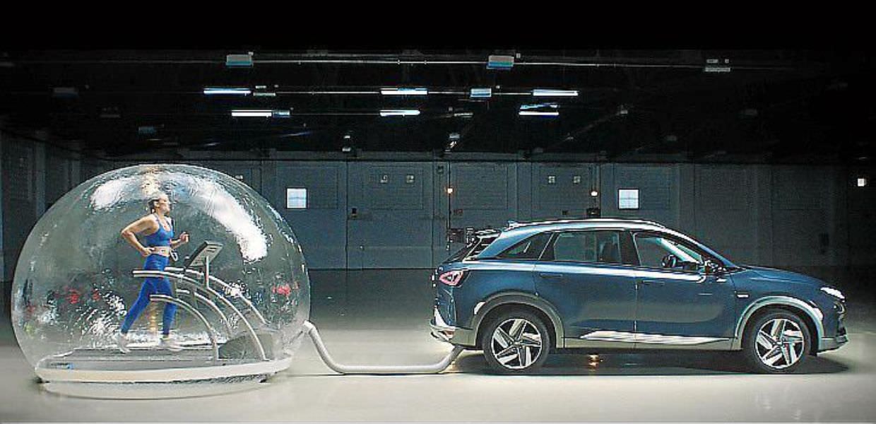 Nuotatrice in allenamento all'interno di una bolla, respirando fumi delle emissioni di un'auto a idrogeno in un ambiente controllato.