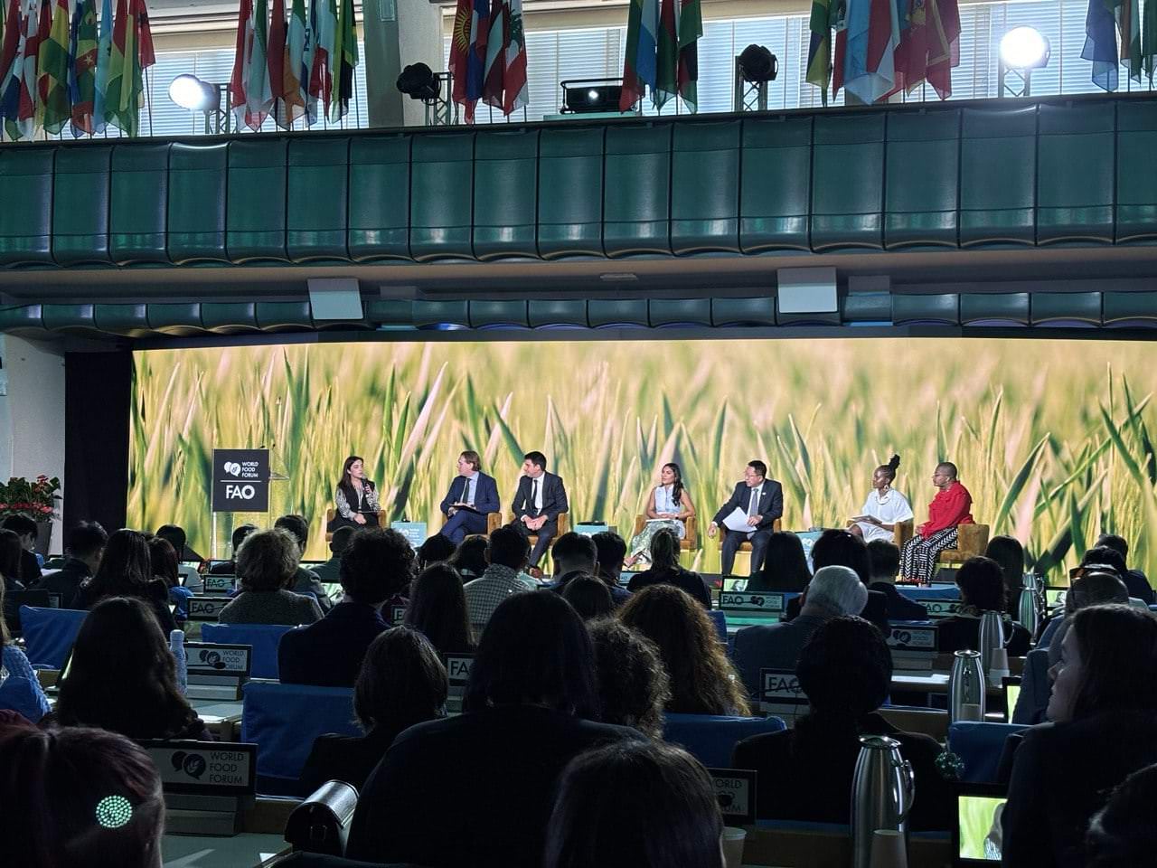 Panoramica del World Food Forum a Roma, con esperti che discutono sostenibilità alimentare in un ambiente decorato da bandiere internazionali.