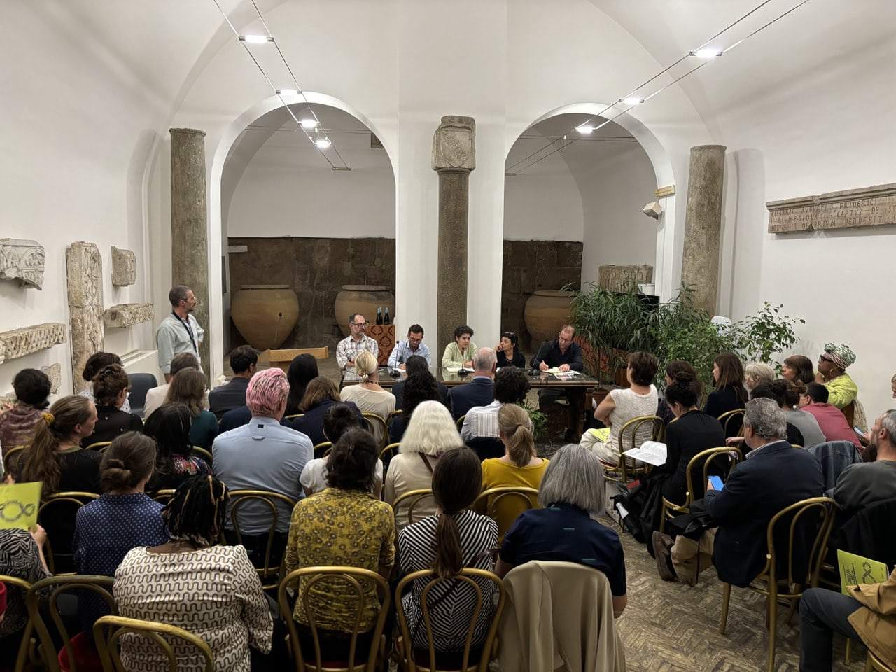 Evento sulla raccolta firme per il diritto al cibo, con cittadini europei in discussione all'interno di uno spazio culturale.