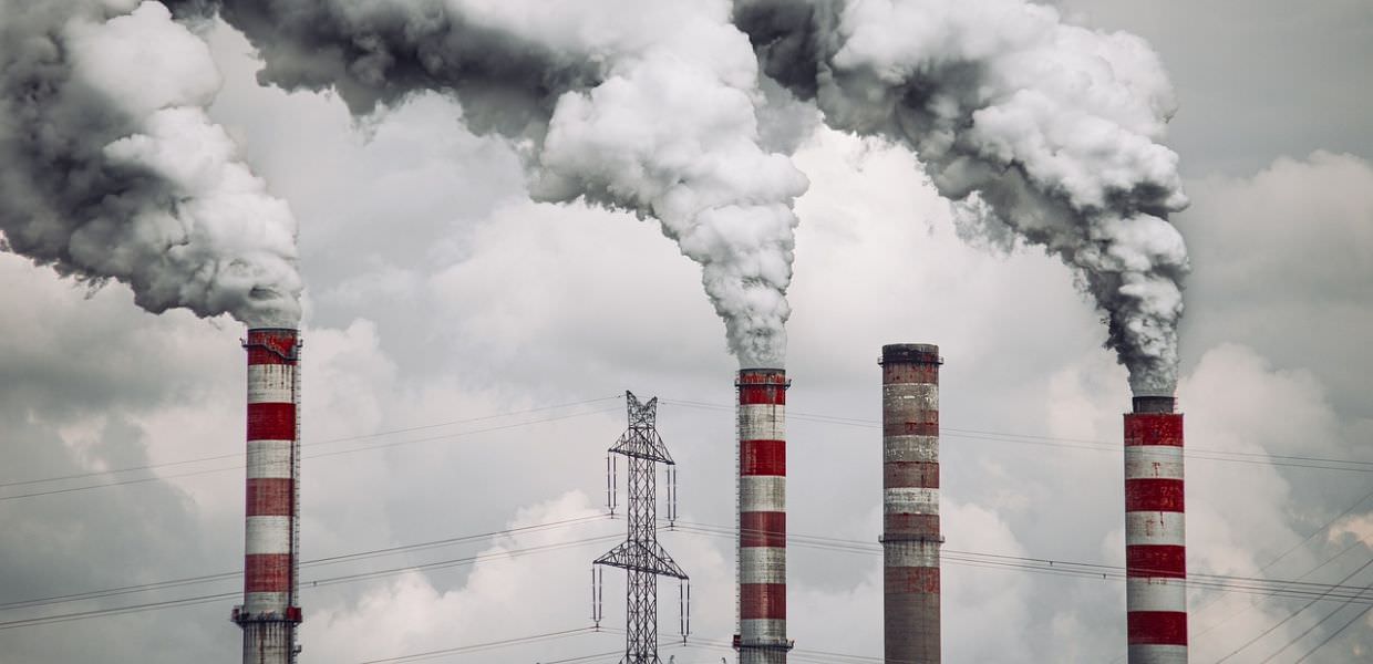 Centrali elettriche a carbone che emettono fumi tossici, simbolo della lotta contro l'inquinamento e il cambiamento climatico.