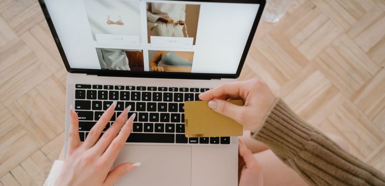 Immagine di un acquisto online per Black Friday 2024, con focus sul legame tra sconti e impatto ambientale. Una mano tiene una carta di credito.