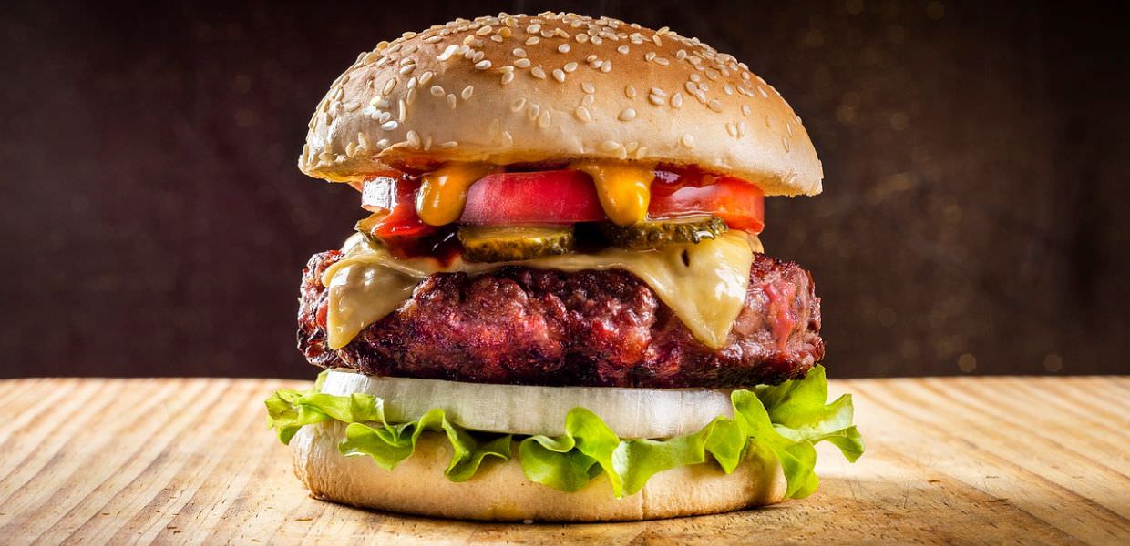 Testo alternativo SEO: Hamburger succulento con ingredienti freschi, simbolo del legame tra consumo di carne e cambiamenti climatici globali.