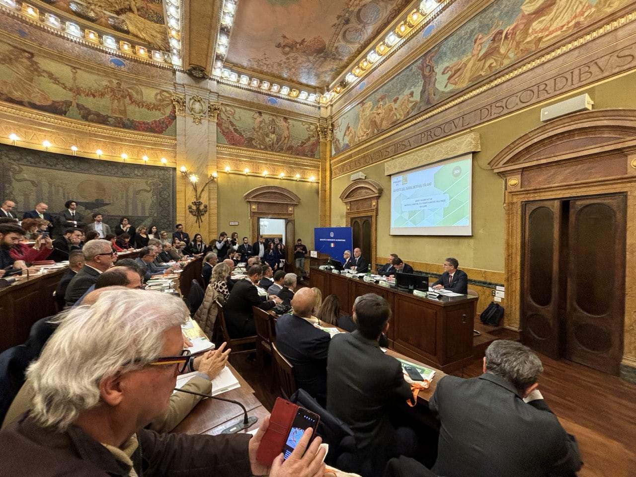 Attendees in a grand hall during a conference on l'export agroalimentare italiano, con focus sui 70 miliardi previsti per il 2024.