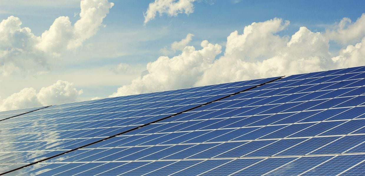 Pannelli solari installati sotto un cielo blu con nuvole, simbolo della leadership della Germania nelle energie rinnovabili rispetto all'Italia.