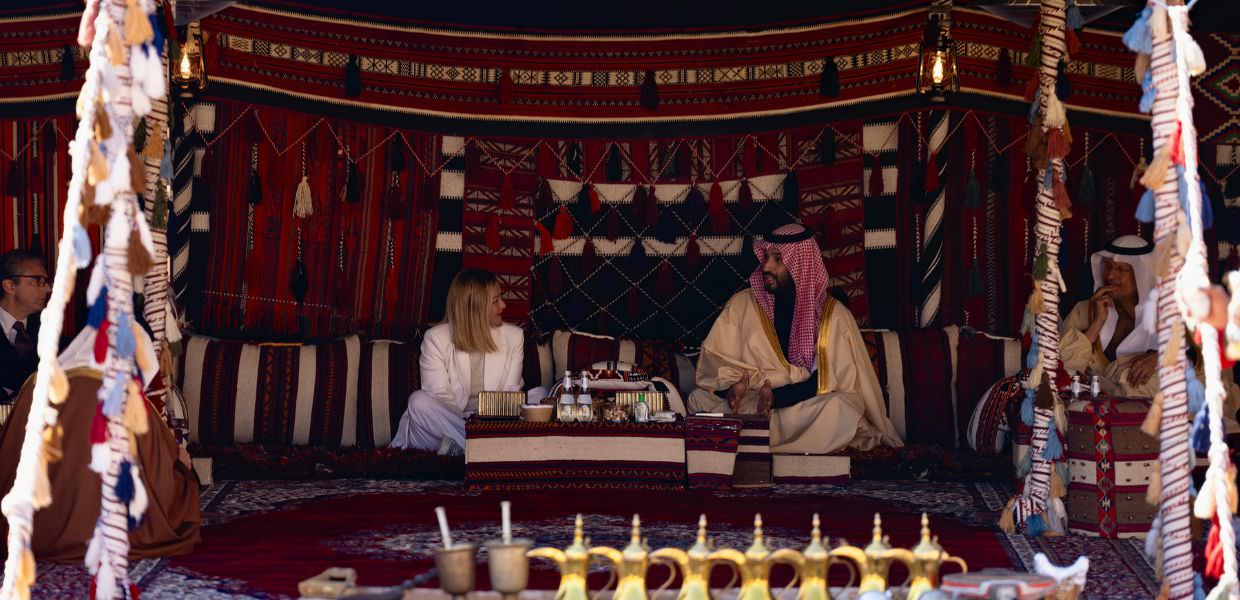 Incontro tra rappresentanti italiani e sauditi in un ambiente tradizionale, discutendo l'accordo sull'energia rinnovabile.