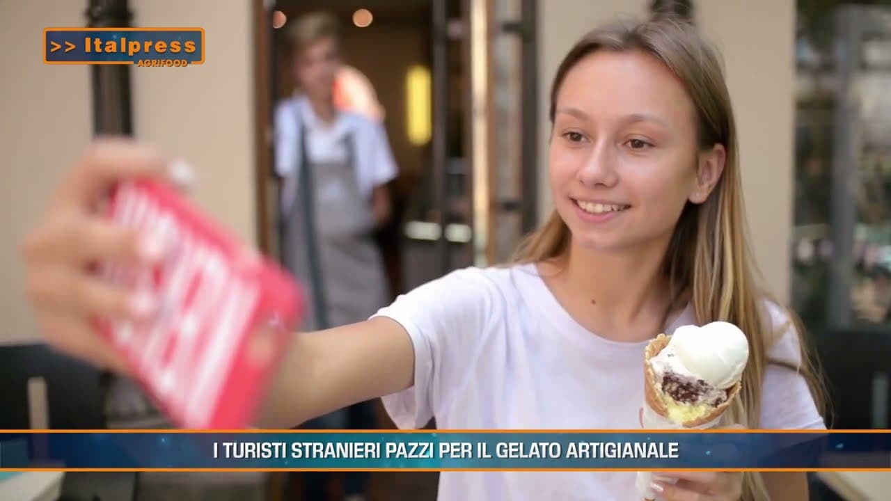 Ragazza sorridente mentre scatta un selfie con un gelato artigianale, rappresentando la passione per il dolce tra i turisti.
